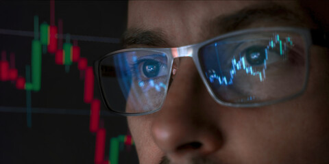 A close-up view of a young trader wearing glasses, with stock or crypto market charts reflecting on the lenses, intensely analyzing financial data for market insights. Bitcoin growth 
