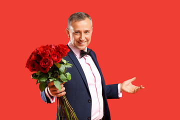 Happy mature man with bouquet of rose flowers on red background. Valentine's day celebration