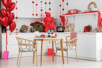 Interior of kitchen decorated for Valentine's Day with dining table, counters and balloons
