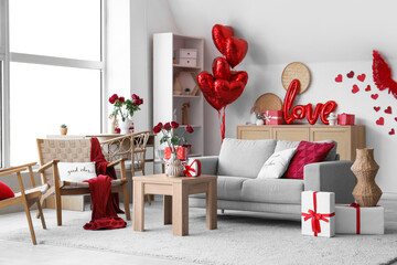 Interior of light living room decorated for Valentine's Day with sofa, table and presents