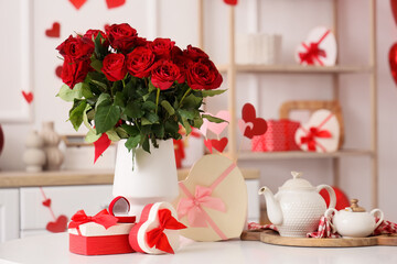 Vase with beautiful rose flowers, engagement ring, tea set and gifts for Valentine's Day on table...