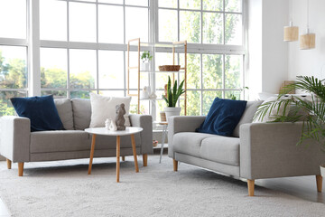 Interior of stylish living room with grey sofas, shelf unit and plants