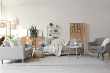 Interior of living room with grey sofas, armchair and plants