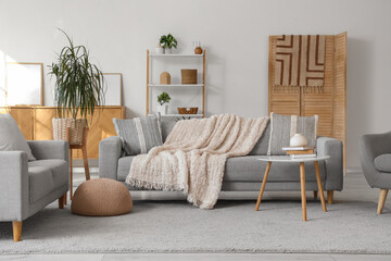 Interior of living room with grey sofas, shelf unit and folding screen