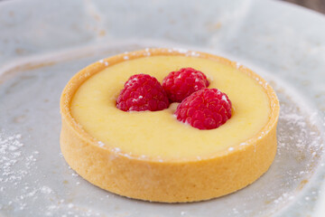 Delicious Lemon Tart with Fresh Raspberries on a Powdered Sugar Plate