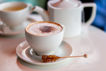 Cozy Cafe Scene With Cappuccino and Tea Set on White Table