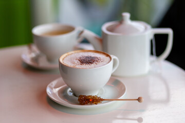Cozy Cafe Scene With Cappuccino and Tea Set on White Table