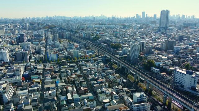 4K aerial view of Tokyo&rsquo;s residential area. Roads and railways intersect under clear skies, capturing urban life.