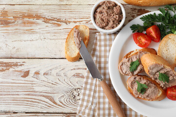 Toasts with tasty pate, tomatoes and parsley and on light wooden background