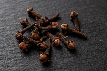 Whole cloves spice over black background. Heap of dry clove buds close-up. Syzygium aromaticum dry...