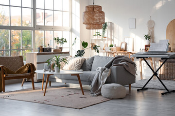 Interior of light living room with sofa, armchair and synthesizer