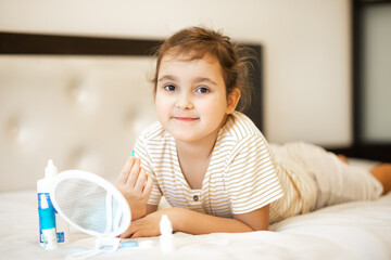 Fototapeta premium Cute little girl inserting contact lenses into her eye. Vision correction and ophthalmology for children.