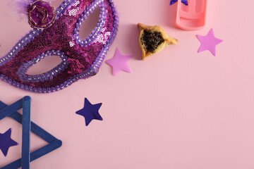 Composition with decor and hamantaschen cookie for Purim holiday on pink background