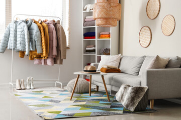 Interior of dressing room with sofa, winter clothes and shelf unit