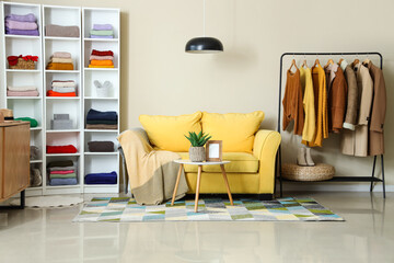 Interior of dressing room with sofa, shelf unit and winter clothes