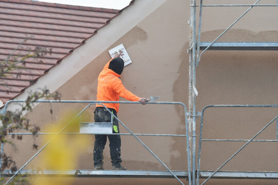 ouvrier ma&ccedil;on sur un &eacute;chaffaudage &eacute;tallant de l'enduit de fa&ccedil;ade