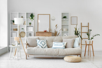 Interior of light living room with beige couch, lamp and plants