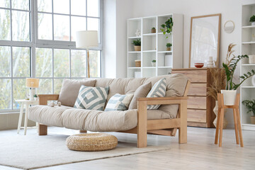 Interior of light living room with beige couch, lamp and plants