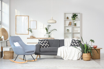 Interior of light living room with sofa, rocking armchair and plants