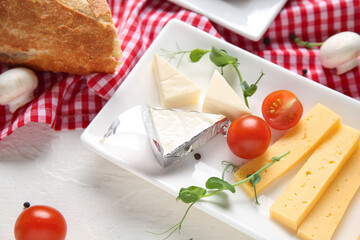 Plate with tasty cheese, micro green, vegetables and bread on light table, closeup