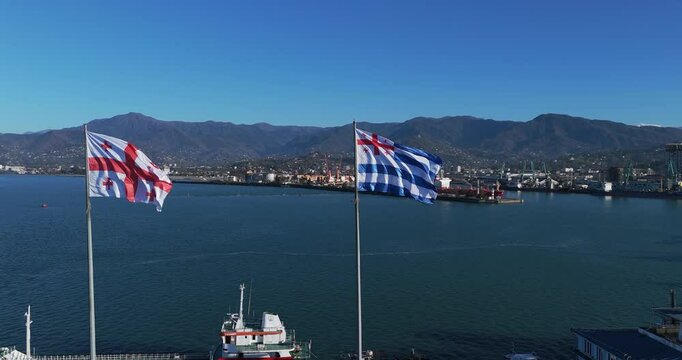 Aerial capture of the seaport with the flags of Adjara and Georgia flying proudly over the city Batumi  and harbor. 