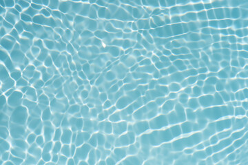 Blue water with ripples on the surface. Defocus blurred transparent blue colored clear calm water surface texture with splashes and bubbles. Water waves with shining pattern texture background.