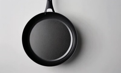 A black frying pan on a light surface, ideal for cooking various dishes.