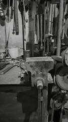 Old tools and a clamp resting on a workbench in a workshop, capturing the essence of craftsmanship and the passage of time.