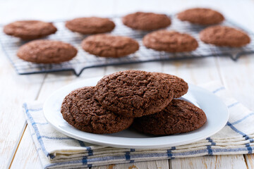 Chocolate brownie cookies with cracks in a ceramic bowl on a white table, selective focus.