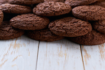 Pile of chocolate brownie cookies with cracks on a light kitchen table, selective focus.