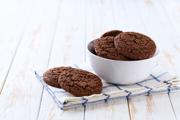 Chocolate brownie cookies with cracks in a ceramic bowl on a white table, selective focus.