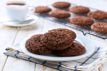 Chocolate brownie cookies with cracks and coffee on a white table, selective focus.