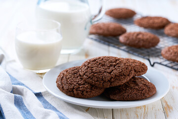 Tasty chocolate cookies and a jug of fresh milk on a light kitchen table, healthy breakfast.