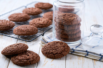Glass jar with american chocolate cookies on a white table.