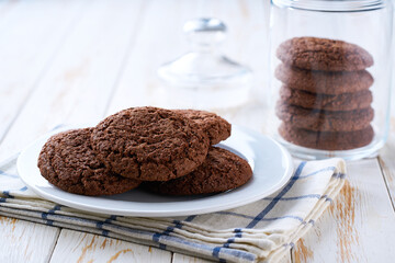 Chocolate brownie cookies with cracks in a jar, on a light kitchen table, with copy space for text.