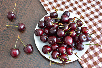 a plate of cherries with a checkered towel on the table 