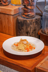 Spaghetti with scallop and truffle sauce decorated with salmon eggs on white dish