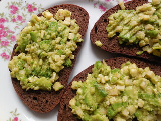 Beautiful unusual sandwiches, finely chopped mixture of cheese, avocado and spices on black bread.