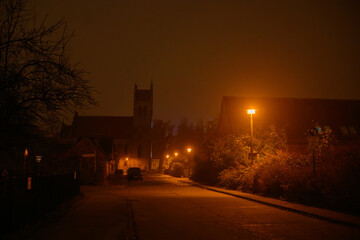 A street is illuminated by streetlights at night.