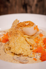 Close up, Spaghetti with scallop and truffle sauce decorated with salmon eggs on white dish