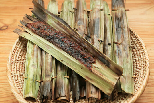 Thai traditional roasted sticky rice flour cake with coconut flesh wrapped in nipa palm leaf called Khanom Chak