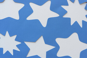stencil with star shapes machine-cut from blank blue paper and arranged on blank paper