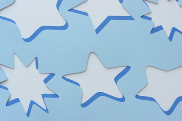 stencils with star shapes machine-cut from blank blue paper and arranged on blank paper