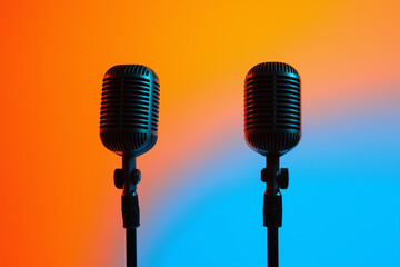 Two vintage microphones on a blurred, colorful background, with soft lighting and shadow effects