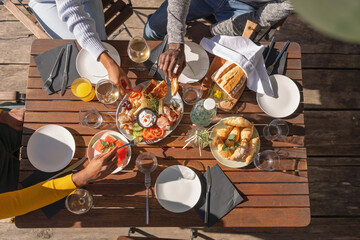 Friends enjoying their vacation, eating lunch outdoor terrace of a glamping resort surrounded by beautiful nature. Top down view