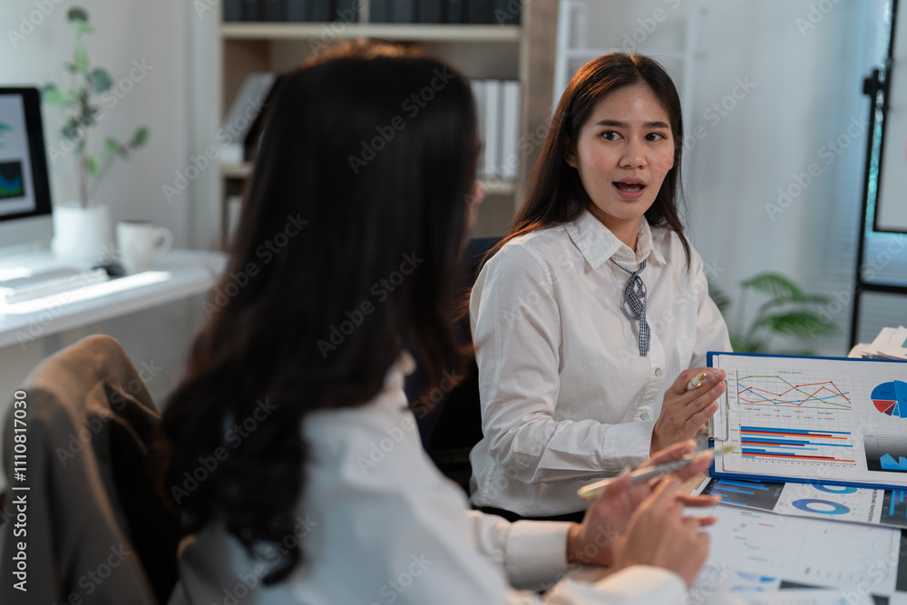 Poster two businesswomen are analyzing financial data and discussing charts and graphs during a productive 