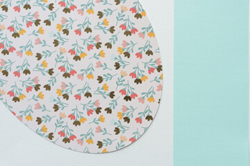 detail of a large ovoid shape machine-cut from decorative scrapbooking paper with florals and blue band on blank paper