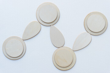 laser-cut wooden tear-shaped and circle objects arranged on blank paper