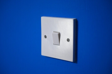 White light switch on a vibrant blue wall