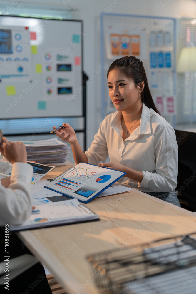 Poster two businesswomen are sitting at a table in a modern office, discussing charts and graphs during a p